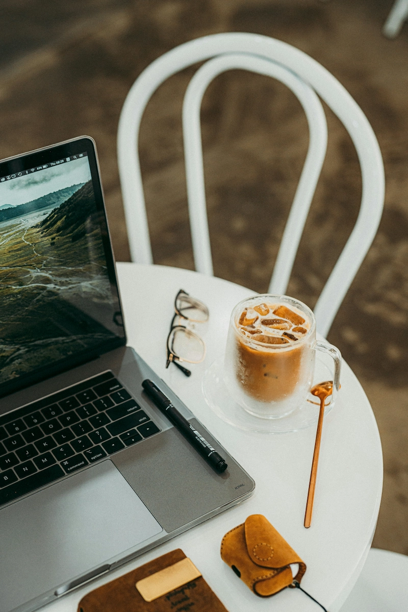 table with laptop, glasses, and a coffee.